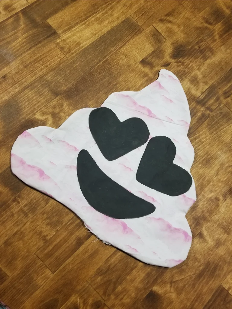 Pink marbled fabric shape with black heart-eyes and smile design on wood floor